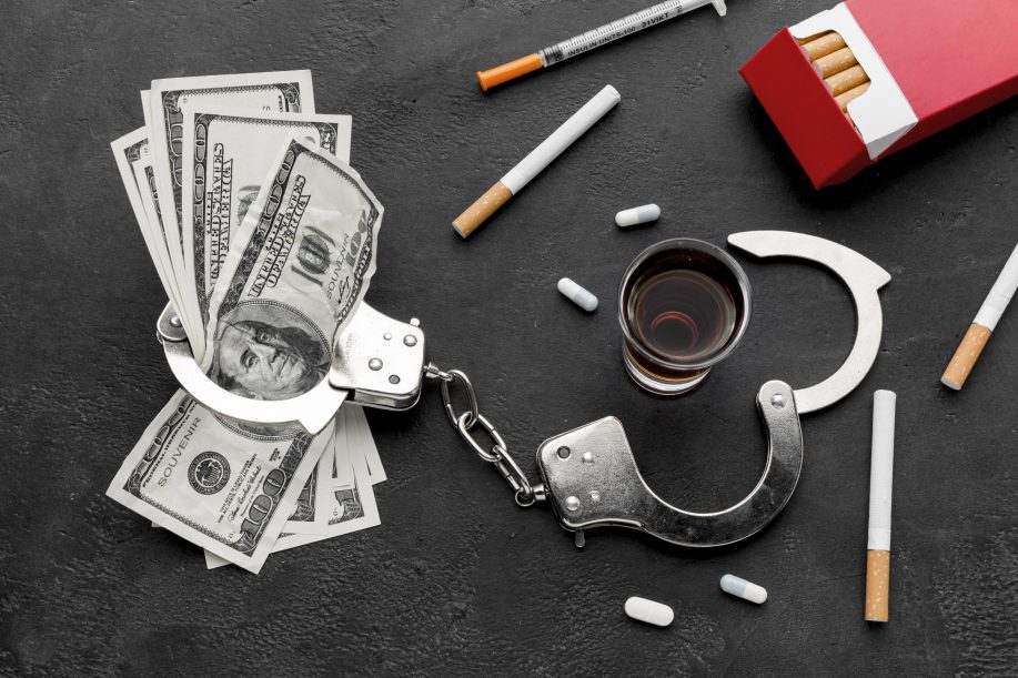 Substances, handcuffs, and dollar bills scattered on a table to symbolise drug trafficking charges in BC